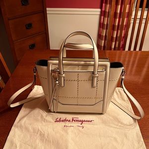 Salvatore Ferragamo white crossbody, purse with gold metal “stitching.”